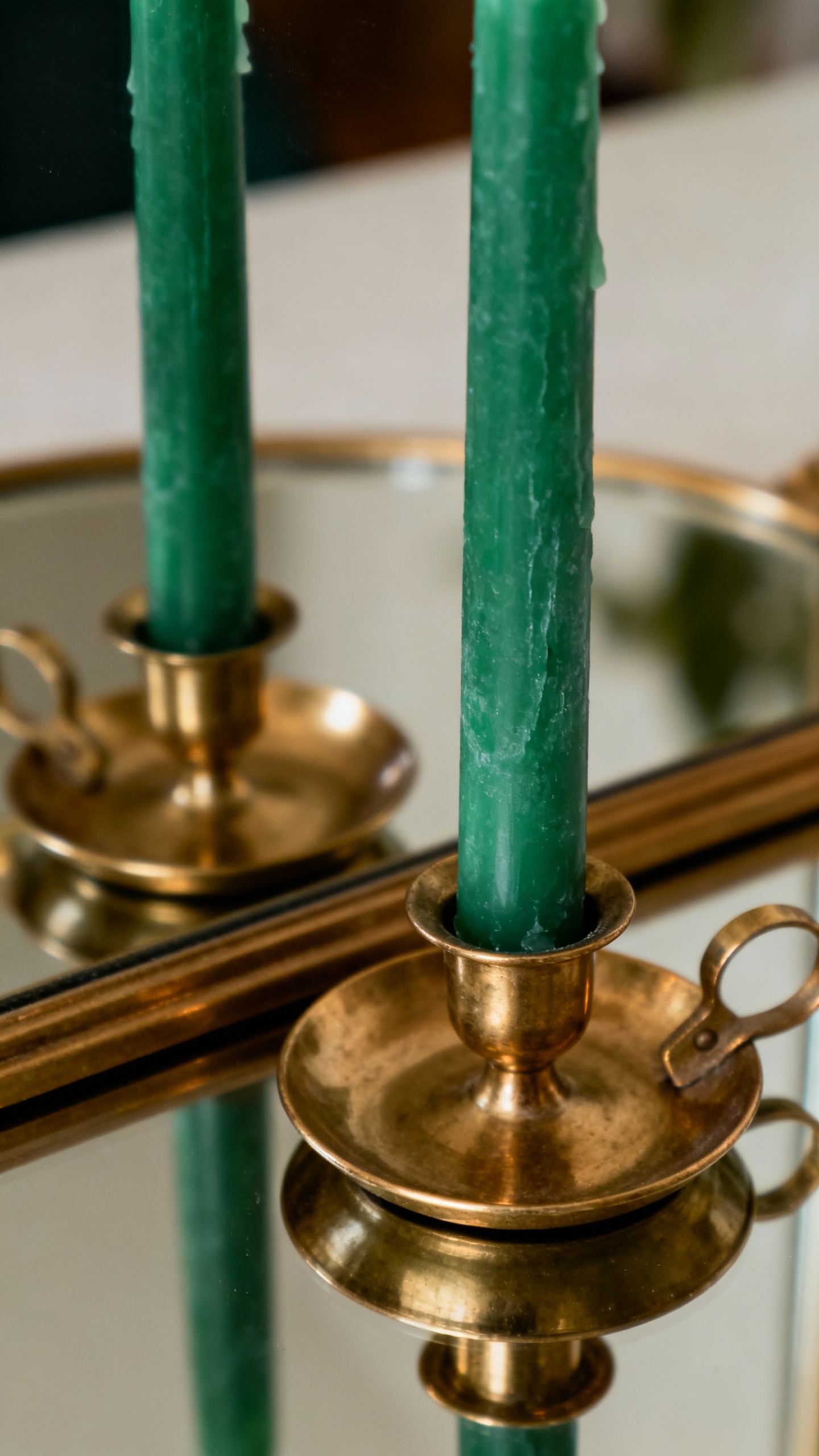 Closeup emerald taper candles in brass holders on mirror