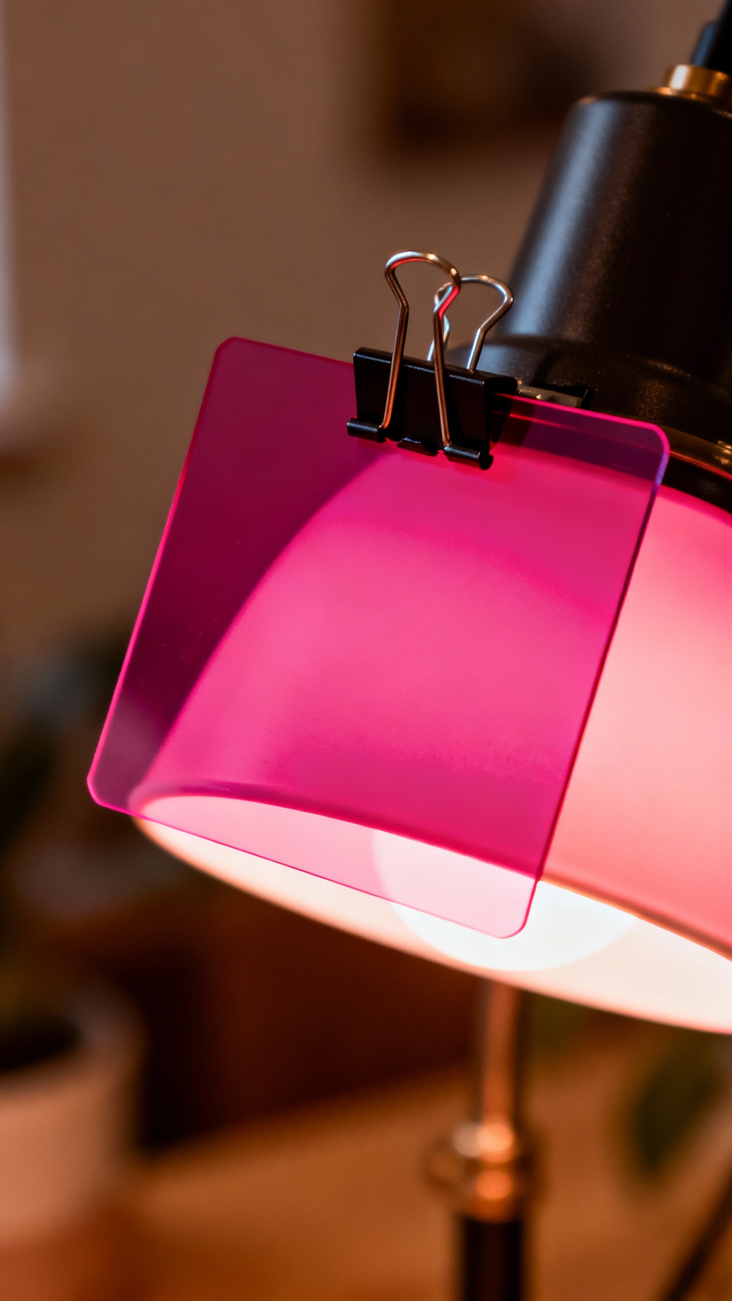 Closeup of colored gel filter clipped on lamp, warm rose glow