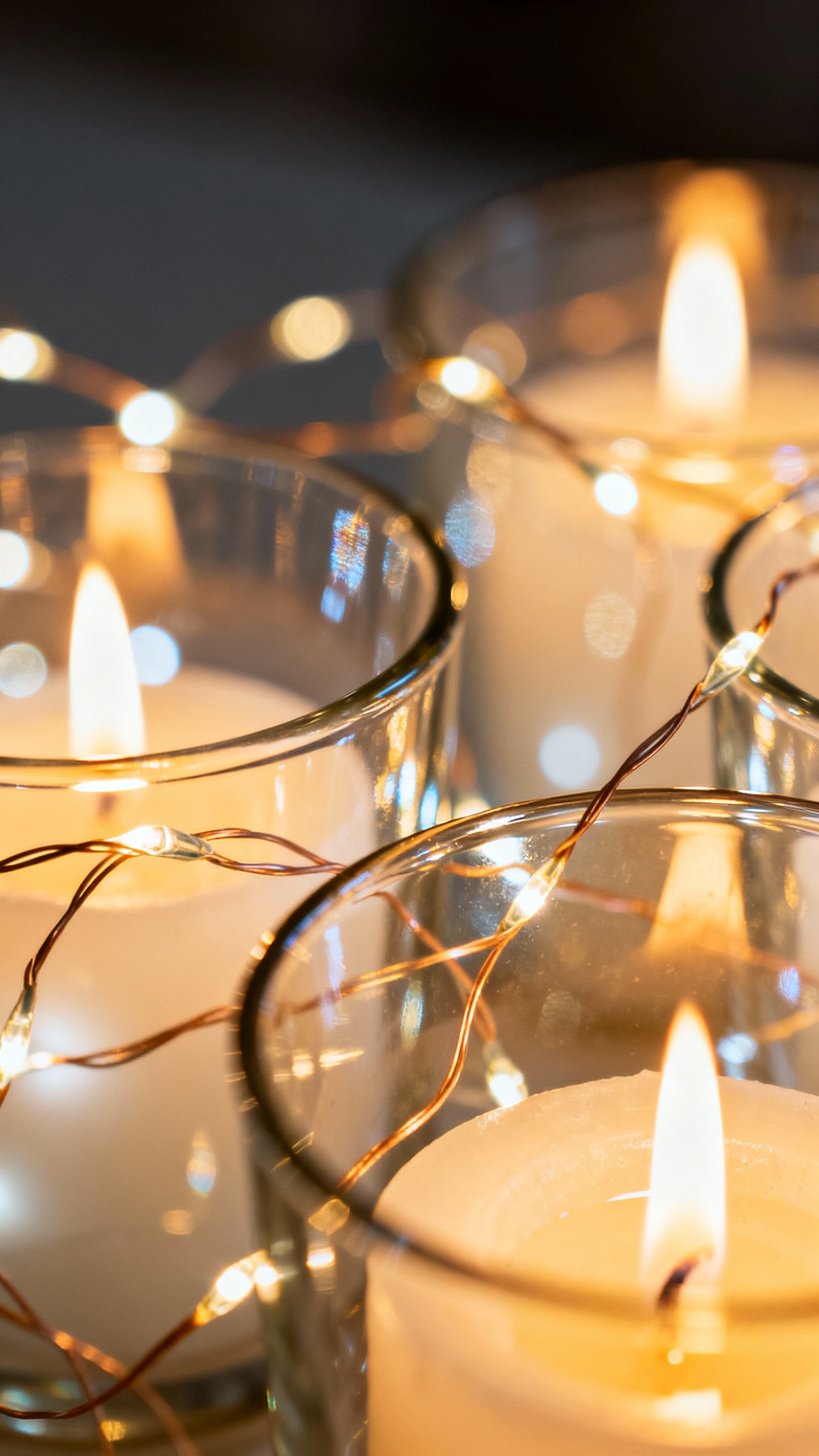 Closeup of lit candles and fairy lights reflecting on glass