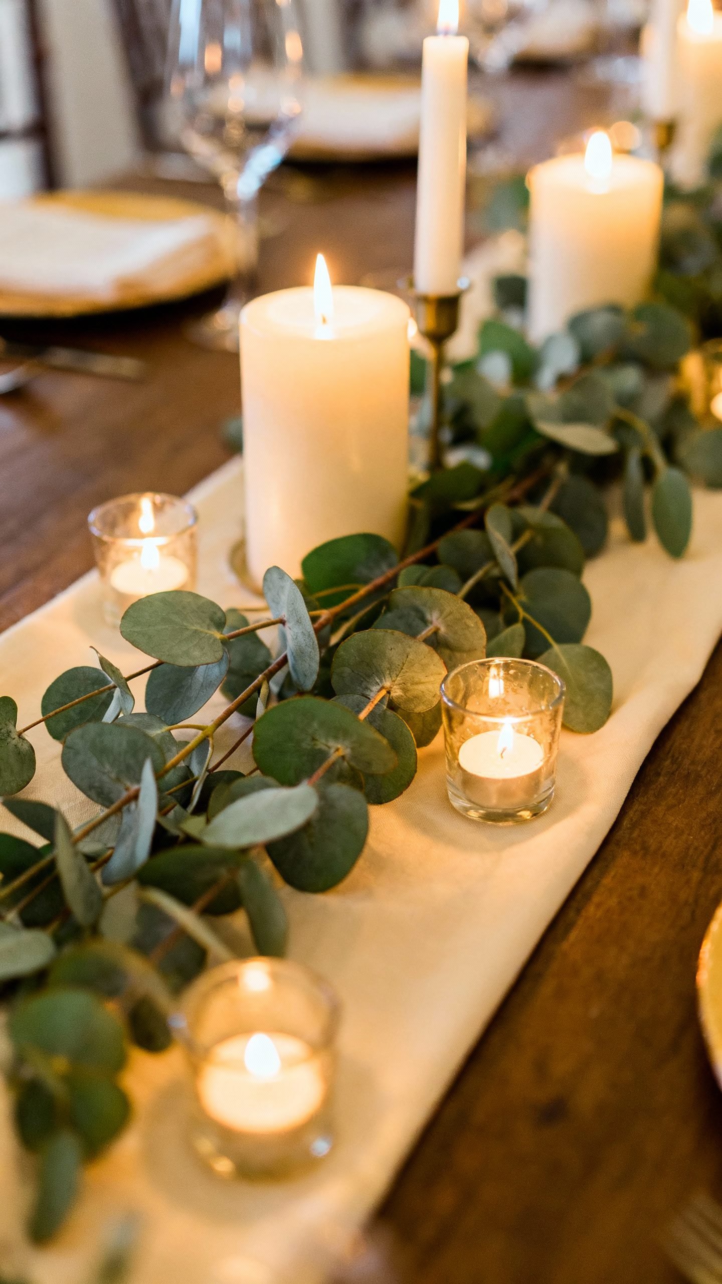 Low centerpiece: eucalyptus branches on runner, tapers and tea lights glowing
