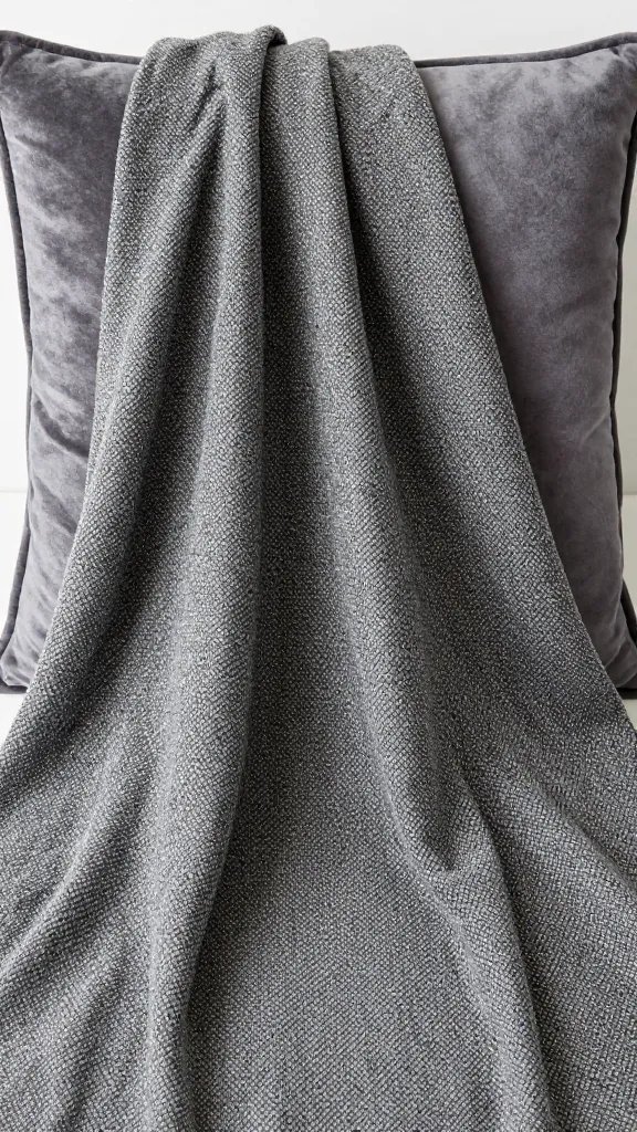 Close-up of a bouclé throw draped over a velvet cushion
